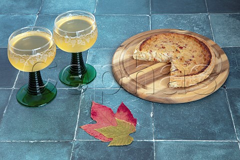 Traditional autumn pairing of Federweisser and onion quiche on a tiled surface with vine leaves