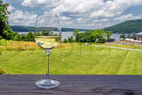 Glass of white wine on table at Domaine Le Seurre Winery with Kueka Lake beyond Hammondsport New York USA Finger Lakes